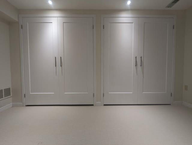 A wall of fitted white wardrobe cabinetry, with flush doors and clean lines